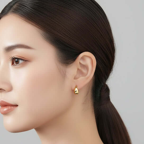 Close-up of an ear wearing a Gold Teardrop Mini Hoop Earrings with a blurred background