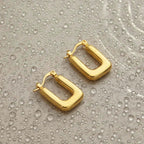 Ceyrah gold hoop earrings on water-dappled surface, modern jewelry design