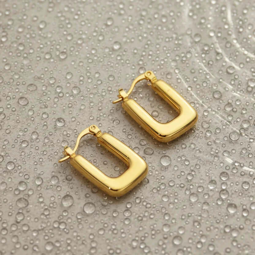 Ceyrah gold hoop earrings on water-dappled surface, modern jewelry design