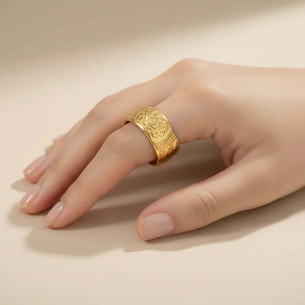 Hand wearing wide gold engraved ring on neutral background, Ceyrah jewelry