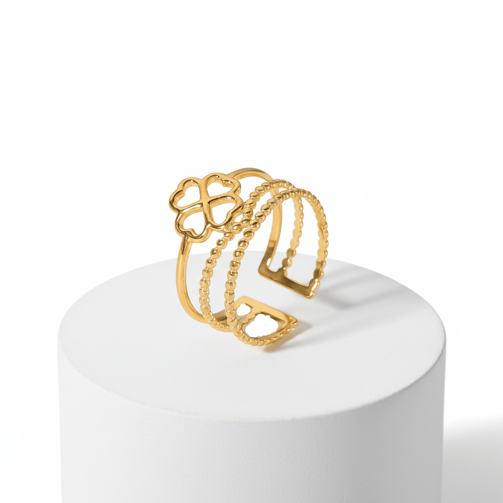 Gold Clover Triple Band Ring displayed on a pedestal, featuring layered smooth, beaded, and geometric designs.