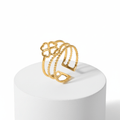 Gold Clover Triple Band Ring displayed on a pedestal, featuring layered smooth, beaded, and geometric designs.