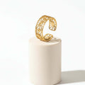 Gold Cut Out Floral Ring displayed on a pedestal showcasing its intricate floral design and open-band silhouette.