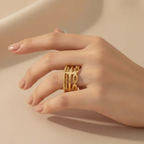 Woman's hand wearing multiple gold rings, Ceyrah jewelry close-up on neutral background
