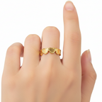 Gold heart-shaped ring on a finger against a white background