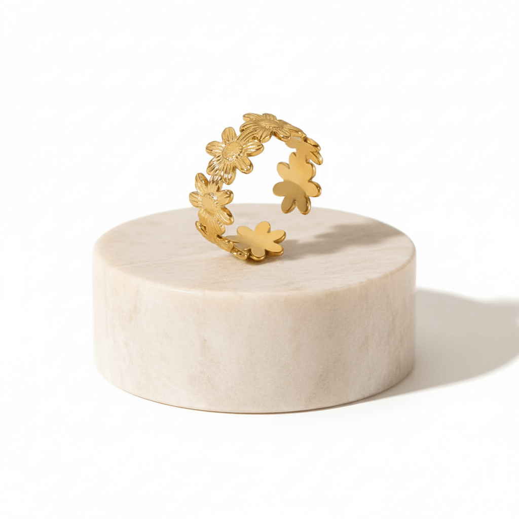 Gold Floral Linked Ring displayed on a marble pedestal, showcasing its intricate flower design.