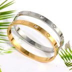 Ceyrah gold and silver clover engraved diamond bangle bracelet on white background with leaves