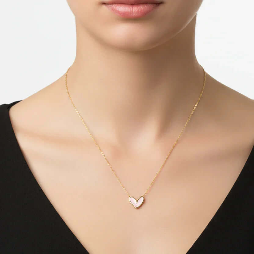 Woman wearing gold heart pendant necklace from Ceyrah on black dress