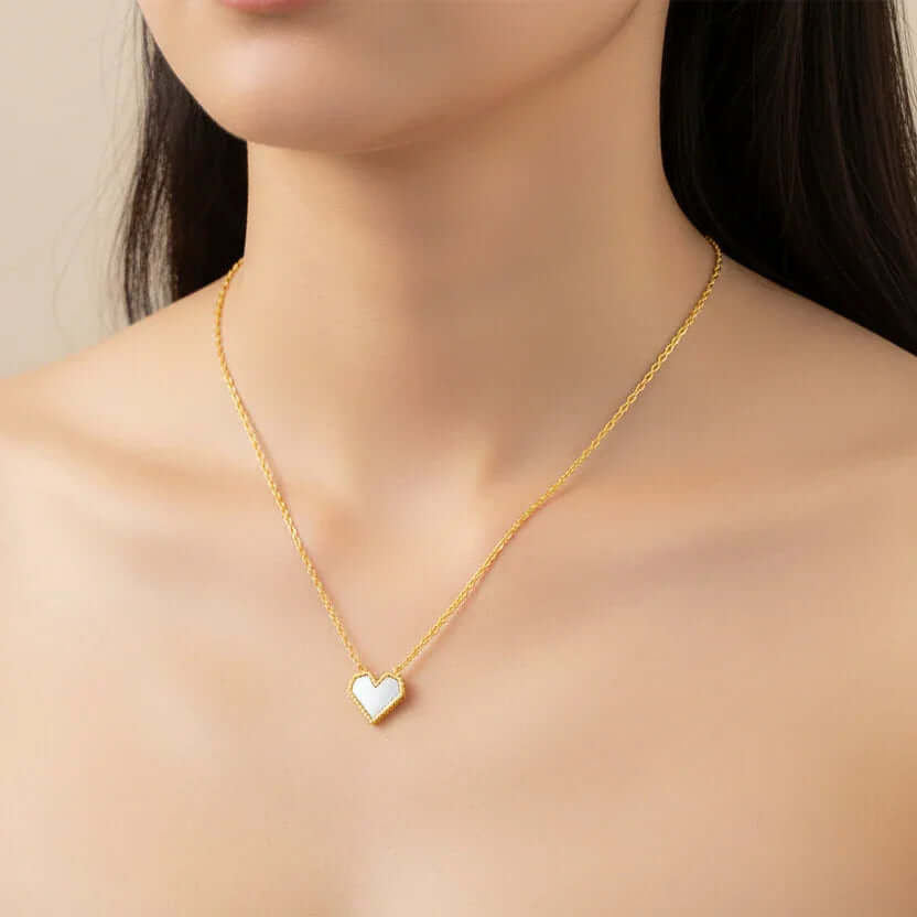 Woman wearing Ceyrah gold heart pendant necklace on bare neck, minimal jewelry style