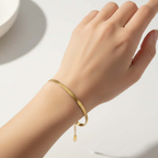 Ceyrah gold bracelet on wrist, minimalist jewelry on light background