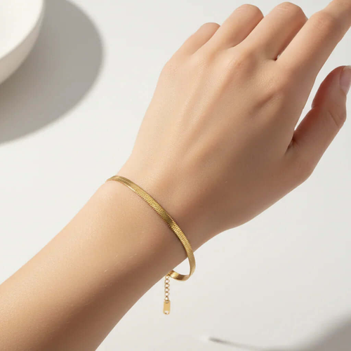 Ceyrah gold bracelet on wrist, minimalist jewelry on light background