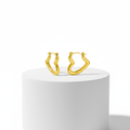 Gold hoop earrings on a white pedestal