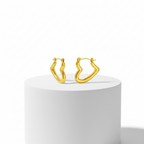 Gold hoop earrings on a white pedestal