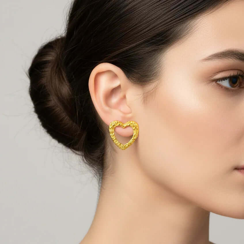 Woman wearing a textured gold heart earring, Ceyrah jewelry collection