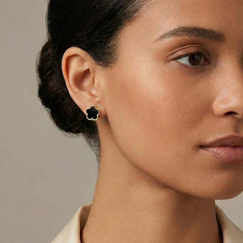 Woman wearing Ceyrah black clover stud earring with gold trim on neutral background