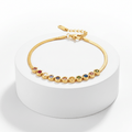 Ceyrah gold bracelet with colorful gemstones, adjustable chain, on white pedestal