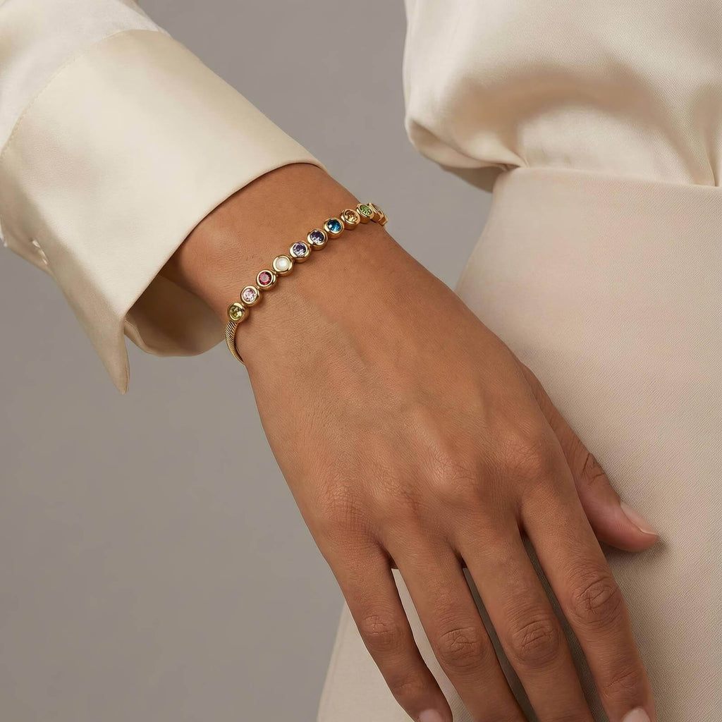 Woman wearing a gold bracelet with colorful gemstones, Ceyrah fashion jewelry