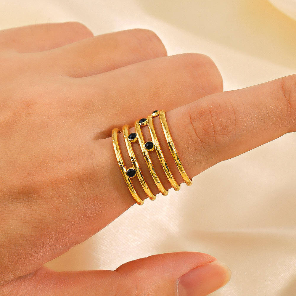 Astra Five‑Band Black Stone Adjustable Ring on a hand against a beige background