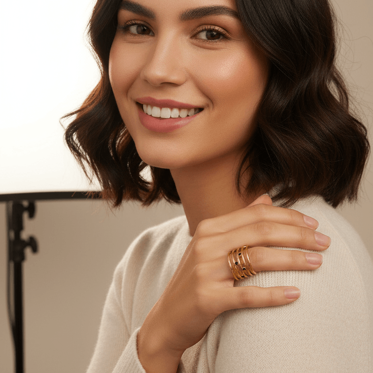 Woman wearing gold rings and a beige sweater with a neutral background