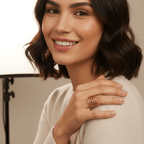 Woman wearing gold rings and a beige sweater with a neutral background