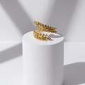 Aurelia Leaf Adjustable Gold Ring on a white cylindrical stand with a light gray background