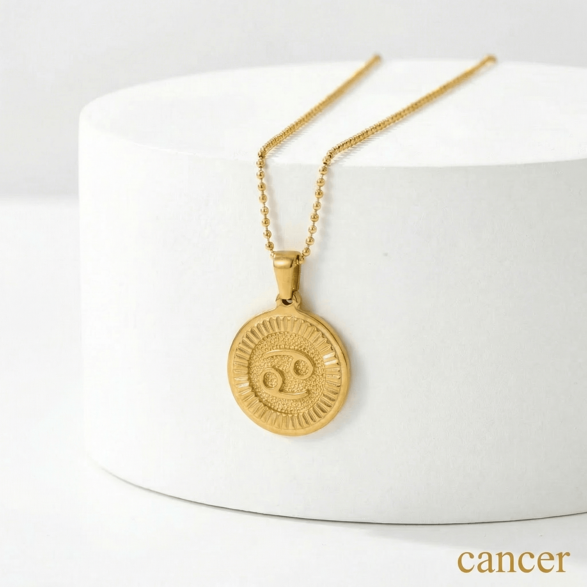 Zodiac Sign Medallion Necklace Gold with a Cancer zodiac sign pendant on a white surface