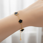 Gold Five Clover Bracelet showcasing black floral motifs on a gold-tone chain worn on a wrist.