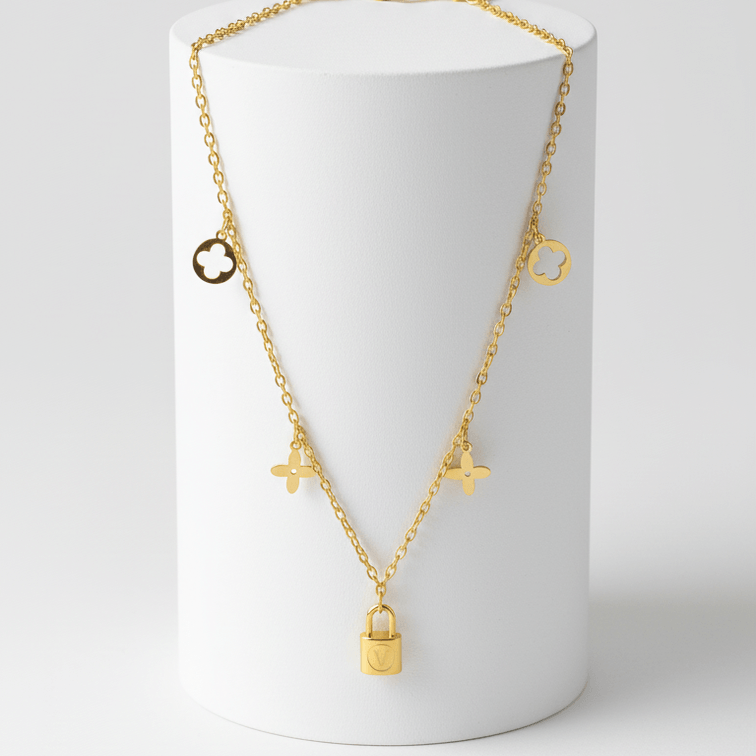 Clover Charm Necklace with Lock Pendant on a white cylindrical stand against a light gray background