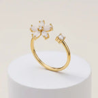 Dainty Bloom Open Gold Adjustable Ring on a white pedestal against a light beige background