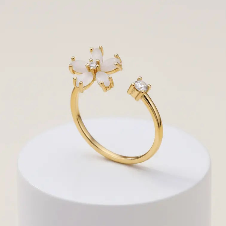 Dainty Bloom Open Gold Adjustable Ring on a white pedestal against a light beige background