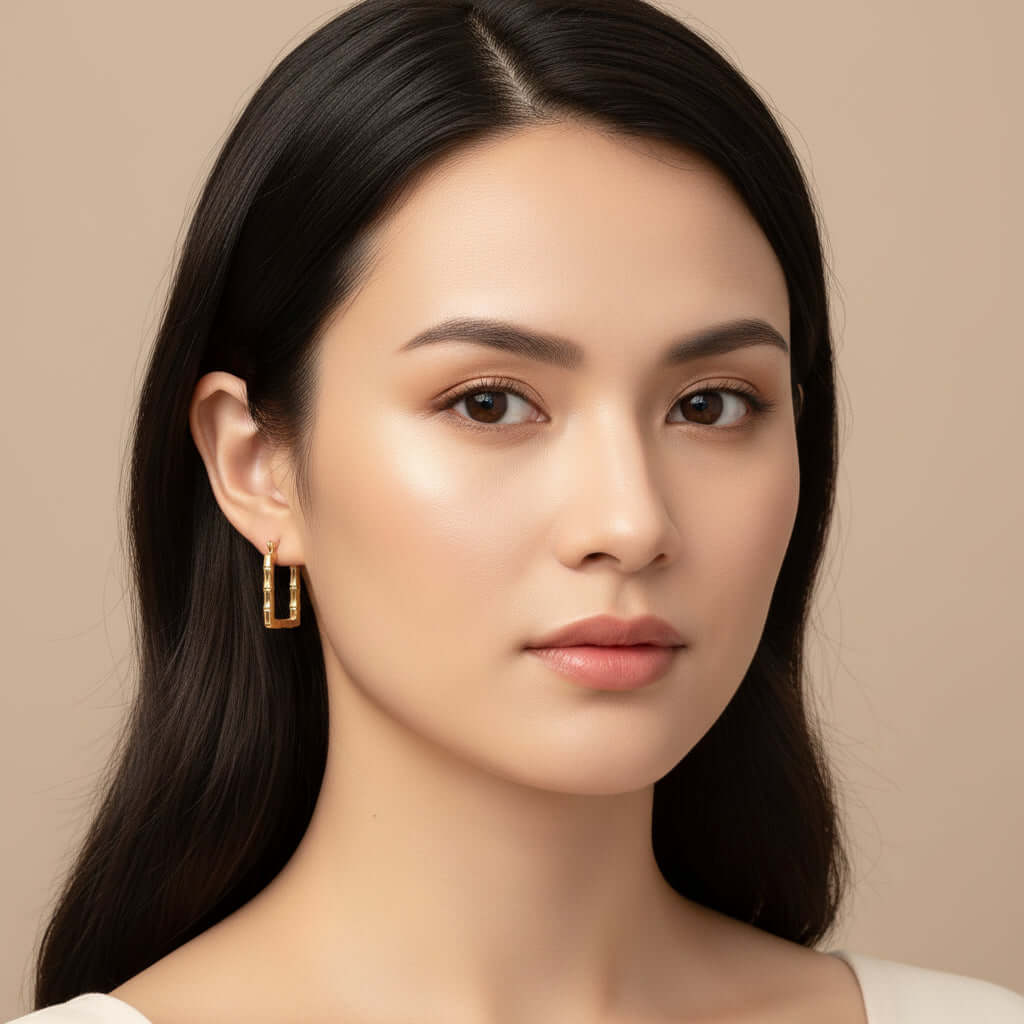 Gold Bamboo Rectangular Hoop Earrings worn by a person with a neutral background