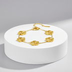 Gold necklace with floral designs on a white pedestal against a gray background
