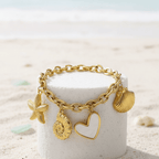 Gold Coastal Charm Bracelet on a white cylindrical container with a beach background