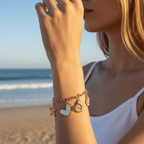 Woman on a beach wearing gold bracelets with heart and circular charms.