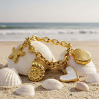 Gold charm bracelet with various charms on a textured stone surface