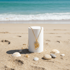 Gold Conch Shell Pendant Necklace displayed on a beach stand surrounded by seashells, reflecting coastal elegance.