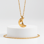 Gold necklace with a crescent moon pendant on a white background