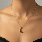 Close-up of a woman wearing a gold necklace with a crescent moon pendant on a neutral background.