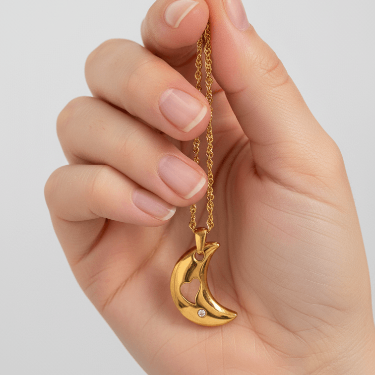 Hand holding Gold Crescent Moon Necklace with a moon-shaped pendant against a light gray background