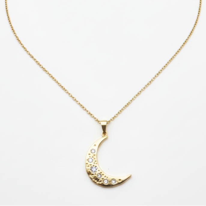 A Gold Crescent Moon Necklace suspended from a delicate gold chain against a plain white background.