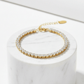 Gold Crystal Tennis Classic Bracelet with clear stones on a white marble surface
