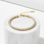 Gold Crystal Tennis Classic Bracelet with clear stones on a white marble surface