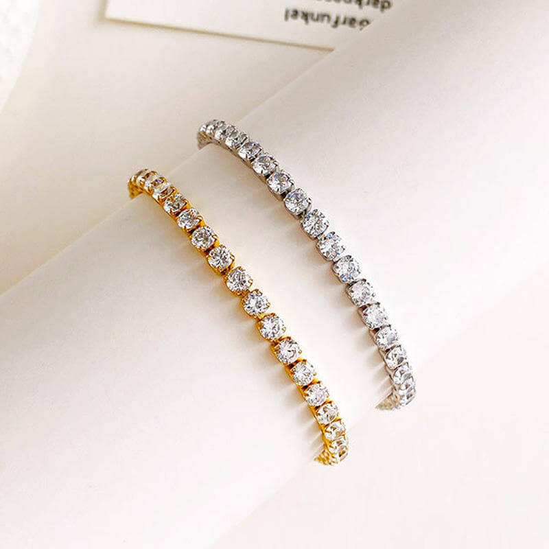 Two diamond Gold Crystal Tennis Classic Bracelet, one gold and one silver, on a light background.