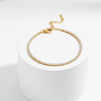 Gold Crystal Tennis Mini Bracelet on a white cylindrical stand with a white background