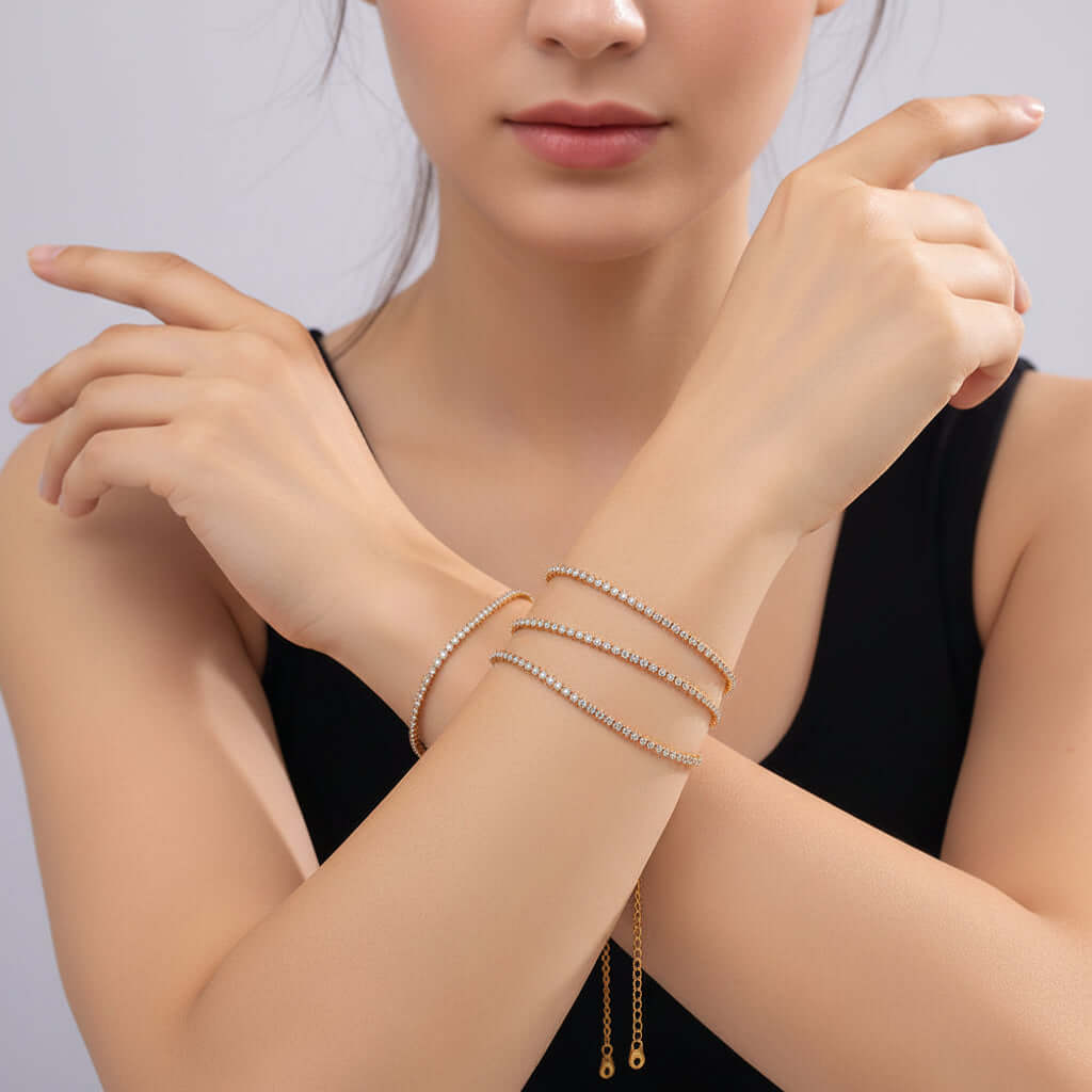 Close-up of a person's wrist with multiple gold bracelets on a neutral background