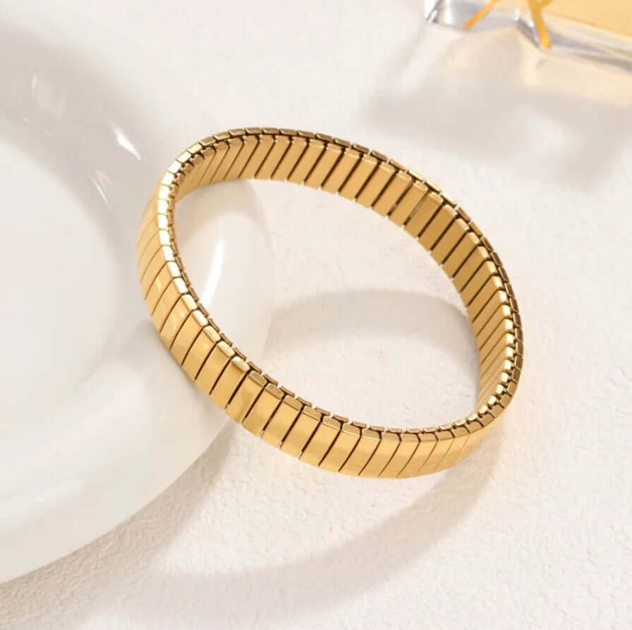 Gold Elastic Stainless Steel Bracelet on a white ceramic dish
