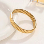 Gold Elastic Stainless Steel Bracelet on a white ceramic dish