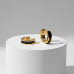Gold Enamel Huggie Hoop Earrings with black interior on a white platform against a gray background