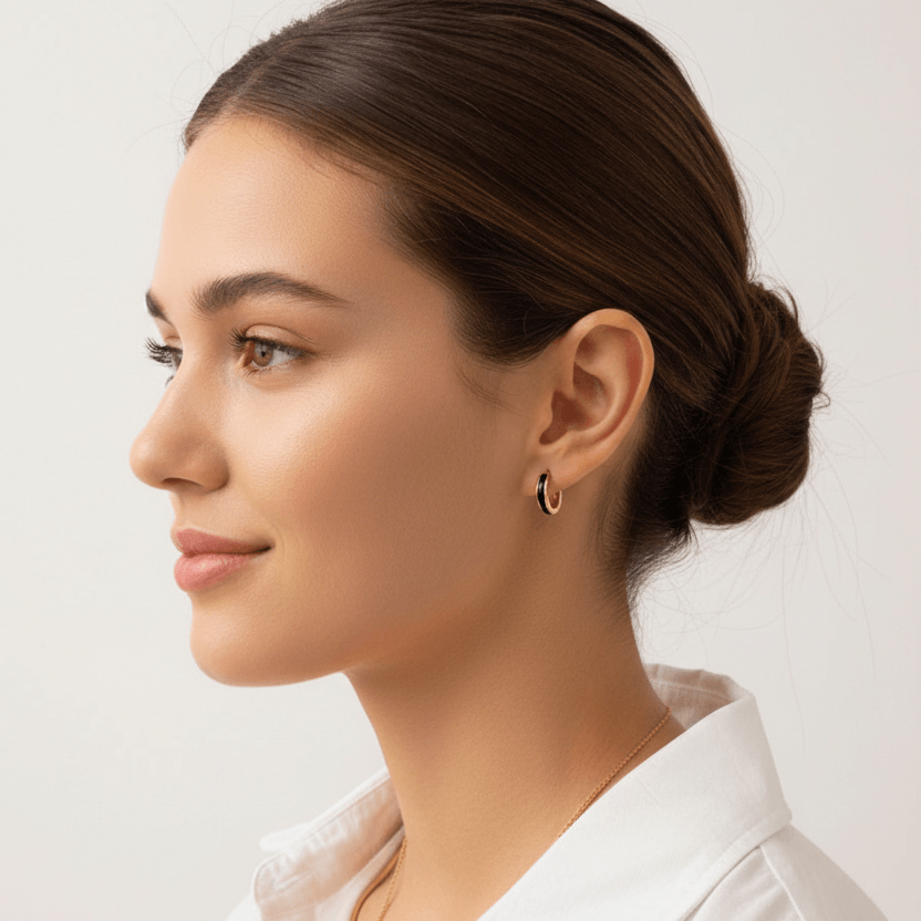 Woman with styled hair and wearing Gold Enamel Huggie Hoop Earrings against a plain background