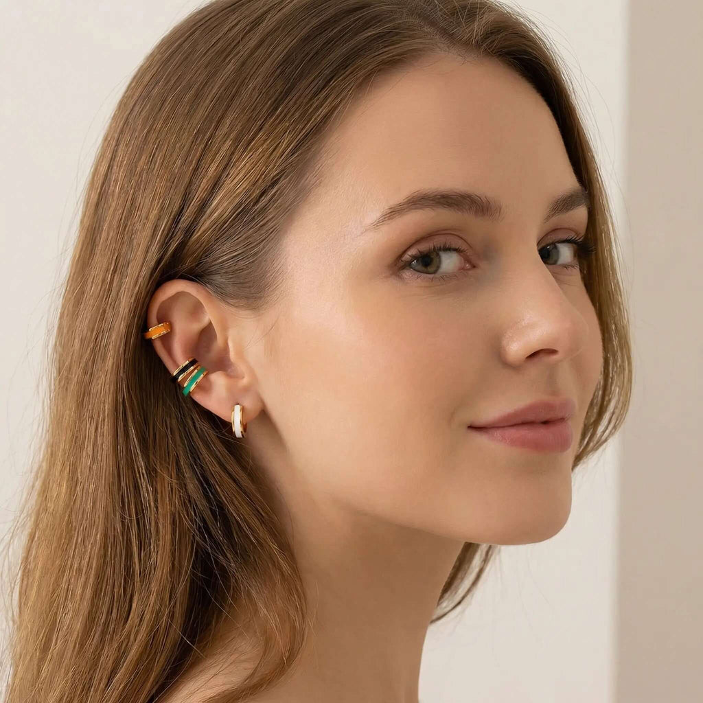 Close-up of a woman wearing colorful Gold Enamel Huggie Hoop Earrings with a neutral background